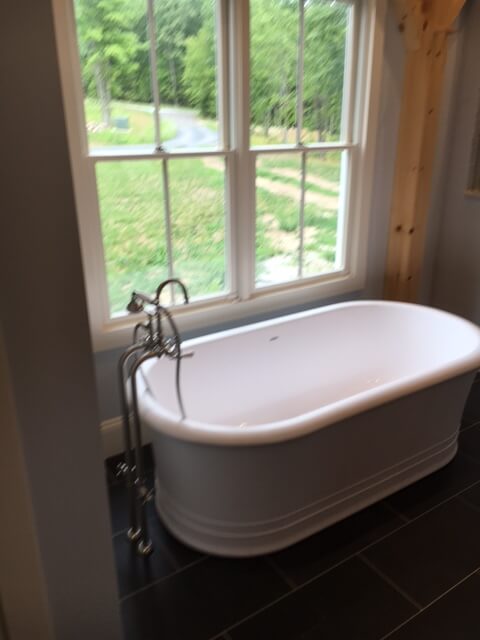 Freestanding soaking tub installed beneath window