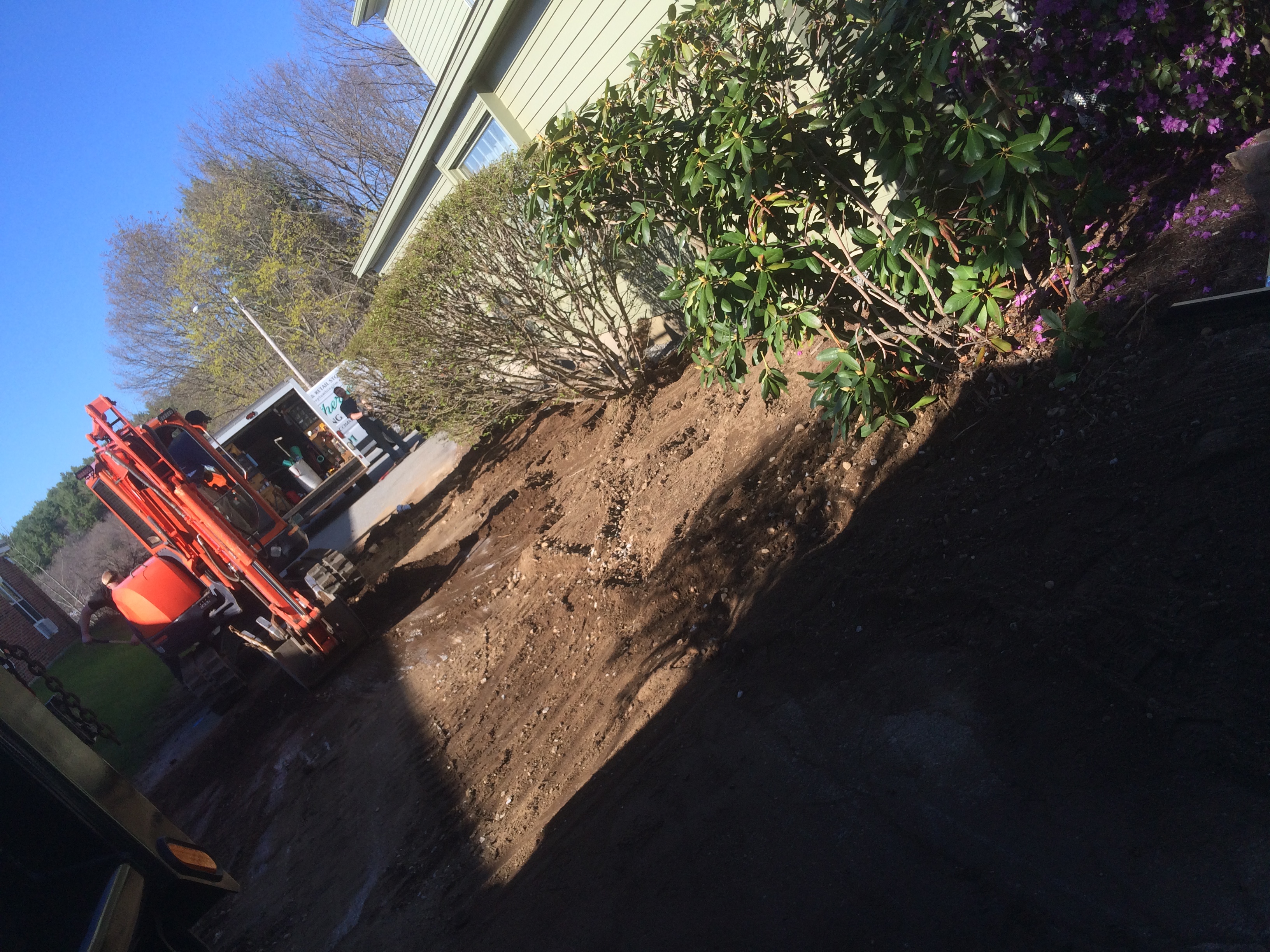 Excavator digging trench beside house